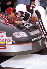 Picture of Dale leaning over and kissing the hood of his car.