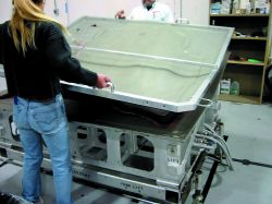 A formed silicone vacuum bag is used to evacuate the air. The reusable bag saves time and results in a smoother part surface than a disposable bagging. Source: MacLean Quality Composites